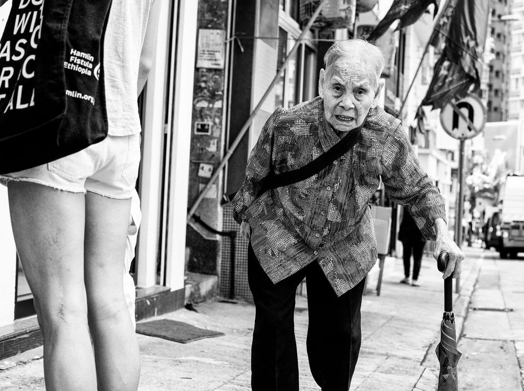 Pudsey Camera Club Member Image Elderly woman with cane on city sidewalk at Pudsey Camera Club.