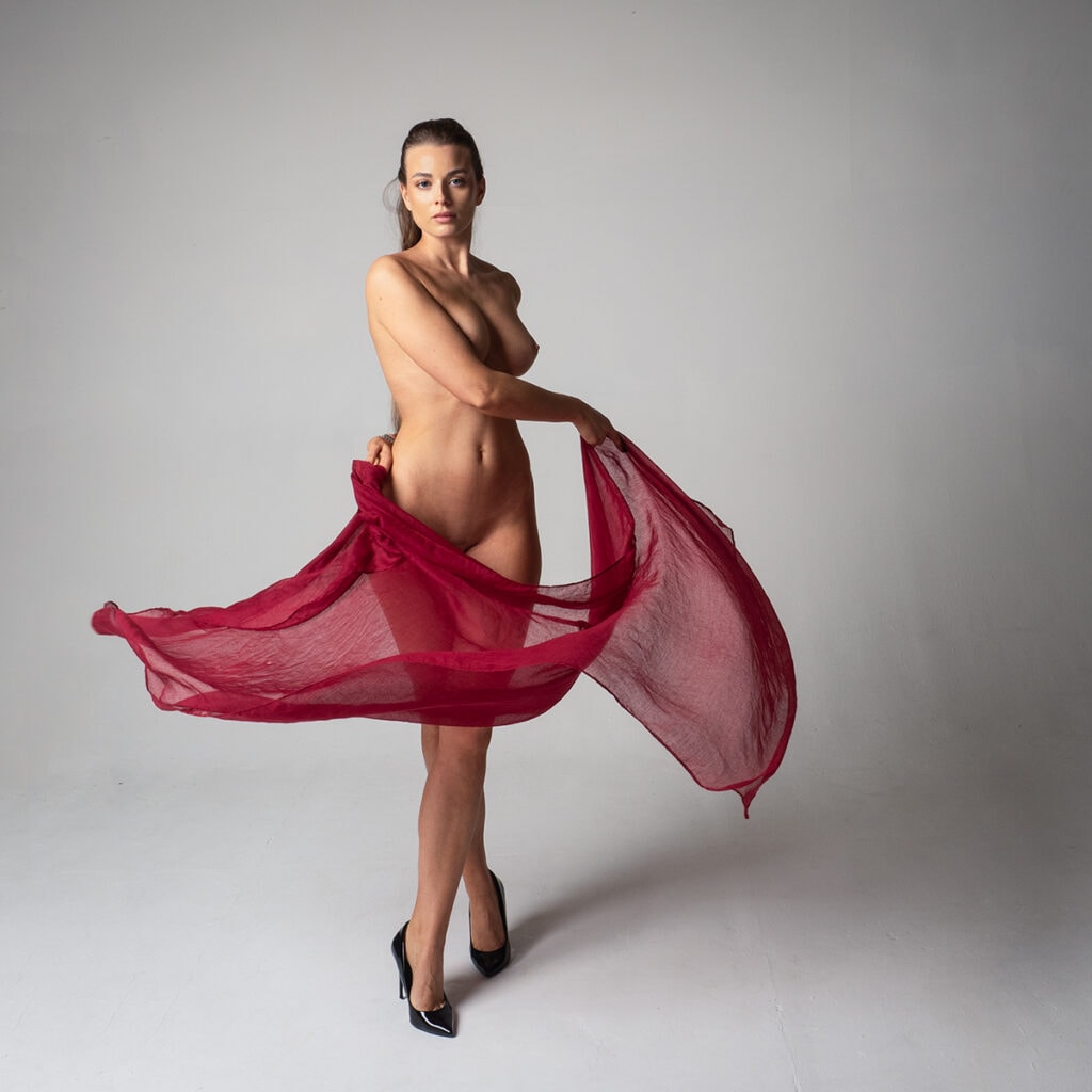 Elegant nude woman holding red sheer fabric, artistic pose, Pudsey Camera Club.