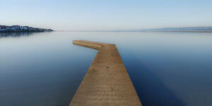 Calm water with a wooden pier extending into the distance, peaceful scene at dawn, Pudsey Camera at.