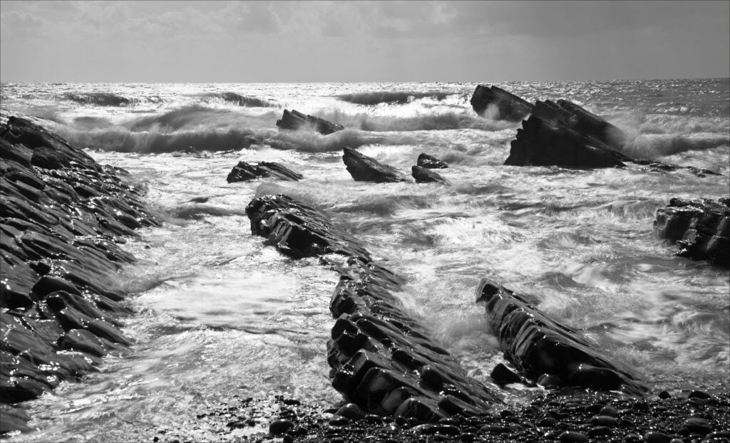 Black and white seascape with rocks and crashing waves at Pudsey Camera Club.